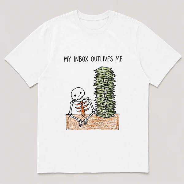 Front view of a White Tee printed with skeleton in a tie slumps at a desk buried under a tall stack of envelopes and the caption MY INBOX OUTLIVES ME